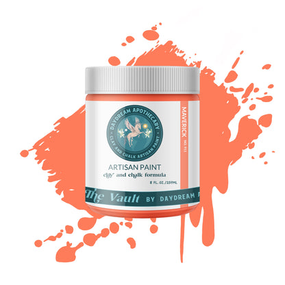 A can of orange chalk paint with the label 'Artisan Paint' and a paintbrush with orange paint on it.