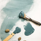 paint brush dipped in a creamy blue gray 